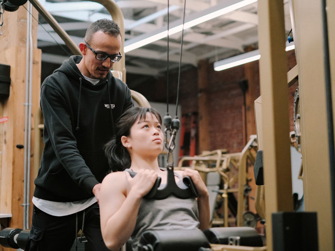 A WESTCA coach guiding a client on the lat pulldown
